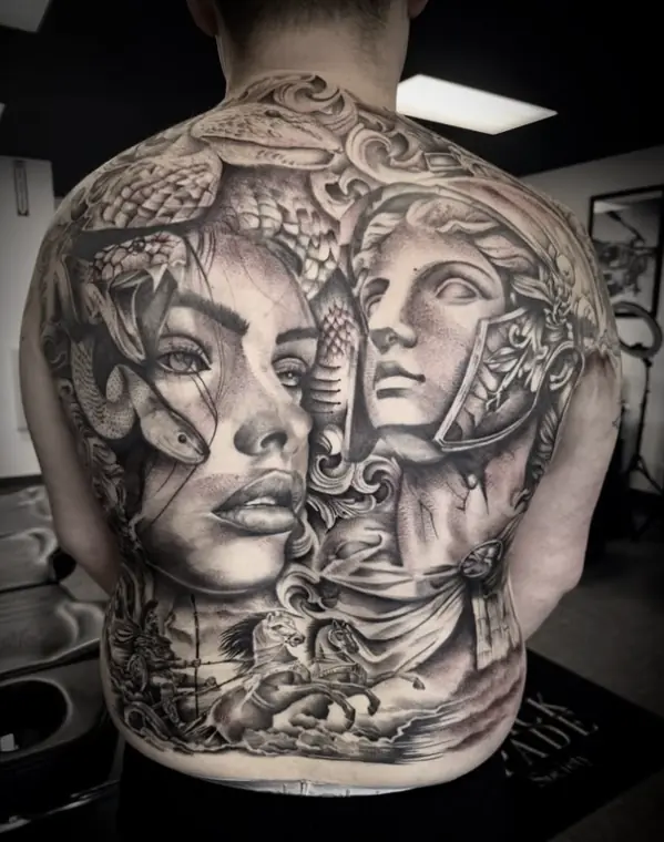 A full back piece in black and grey realism: Medusa with snakes in her hair beside a laurelled marble bust, chariot horses across the lower back.